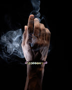 Pulsera zodiacal Escorpio puesta en la muñeca, dedo índice elevado entre el humo