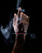Pulsera Zodiacal Capricornio puesta en la muñeca, mano en gesto con humo de copal