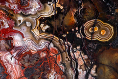 Fotografía macro de la Ágata: bandas de encaje rojas y blancas sobre fondo ámbar oscuro con dos ojos concéntricos. Serie La Disolución, cuadro 08.