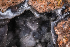 Fotografía macro de la Geoda de Cuarzo: cavidad de cristales grises y brillantes entre bandas de ágata blanca y roca rojiza. Serie La Disolución, cuadro 05.