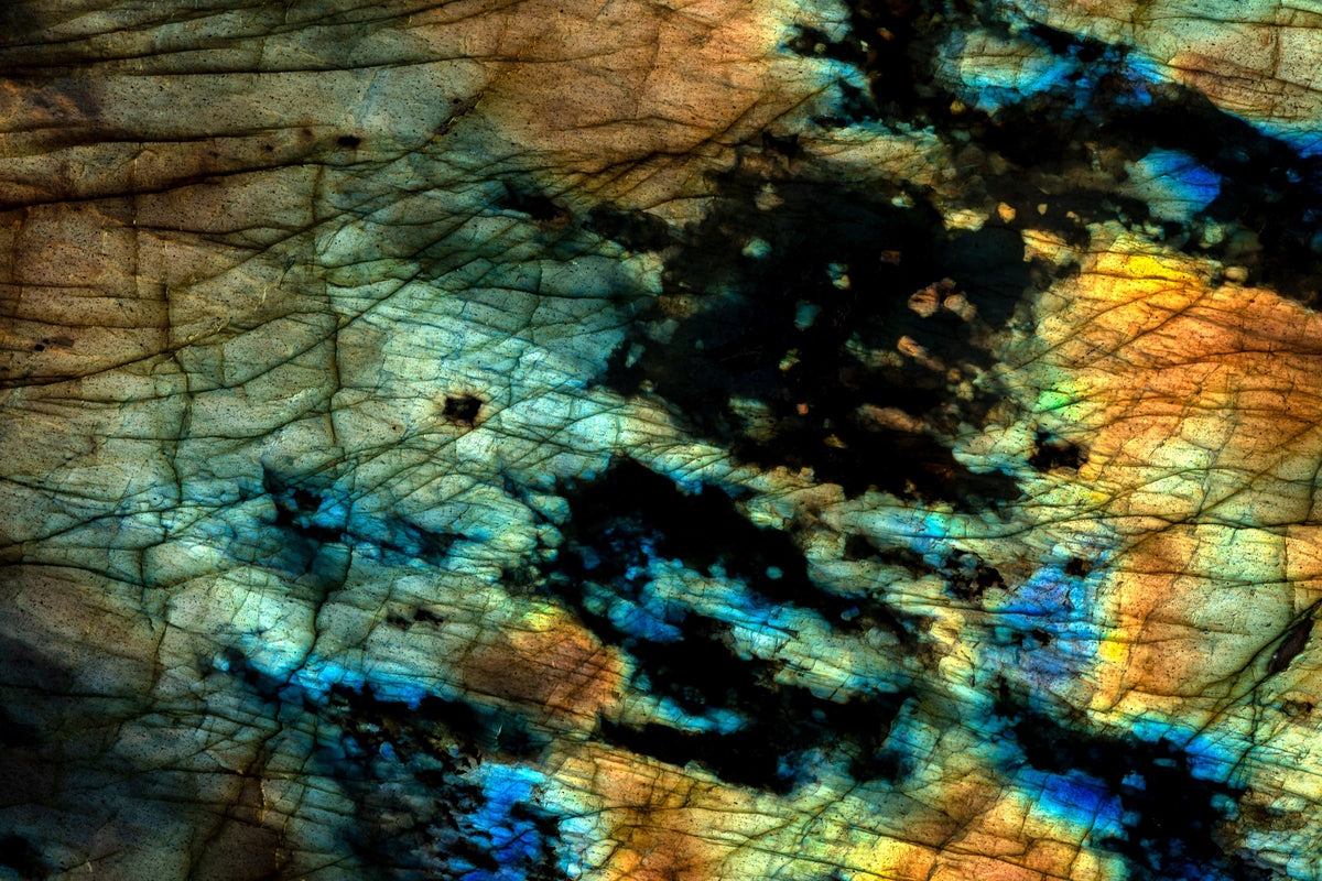 Fotografía macro de la Labradorita: tornasol azul, dorado y naranja bajo una superficie gris con líneas de fractura. Serie La Disolución, cuadro 11.