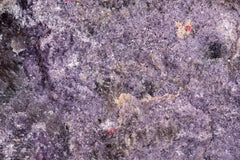 Fotografía macro de la Lepidolita con Rubelita: superficie granular lila con destellos de mica y dos puntos rojos de rubelita. Serie La Disolución, cuadro 18.