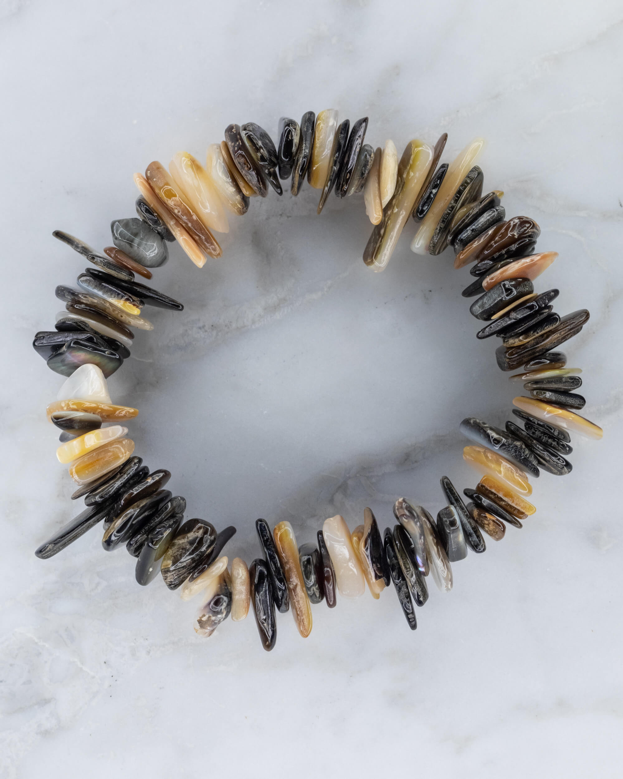 Pulsera de Abulón con cuentas irregulares en círculo sobre superficie de mármol