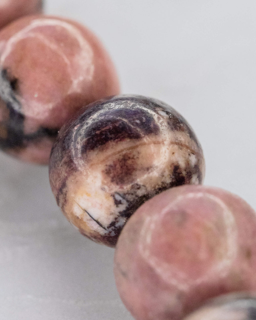 Detalle macro de cuenta de Rodonita Encaje Negro con vetas oscuras y crema