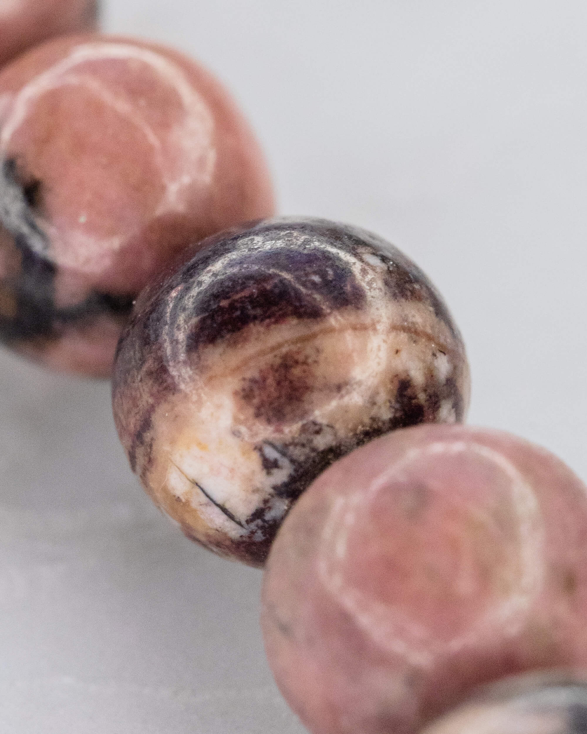 Detalle macro de cuenta de Rodonita Encaje Negro con vetas oscuras y crema