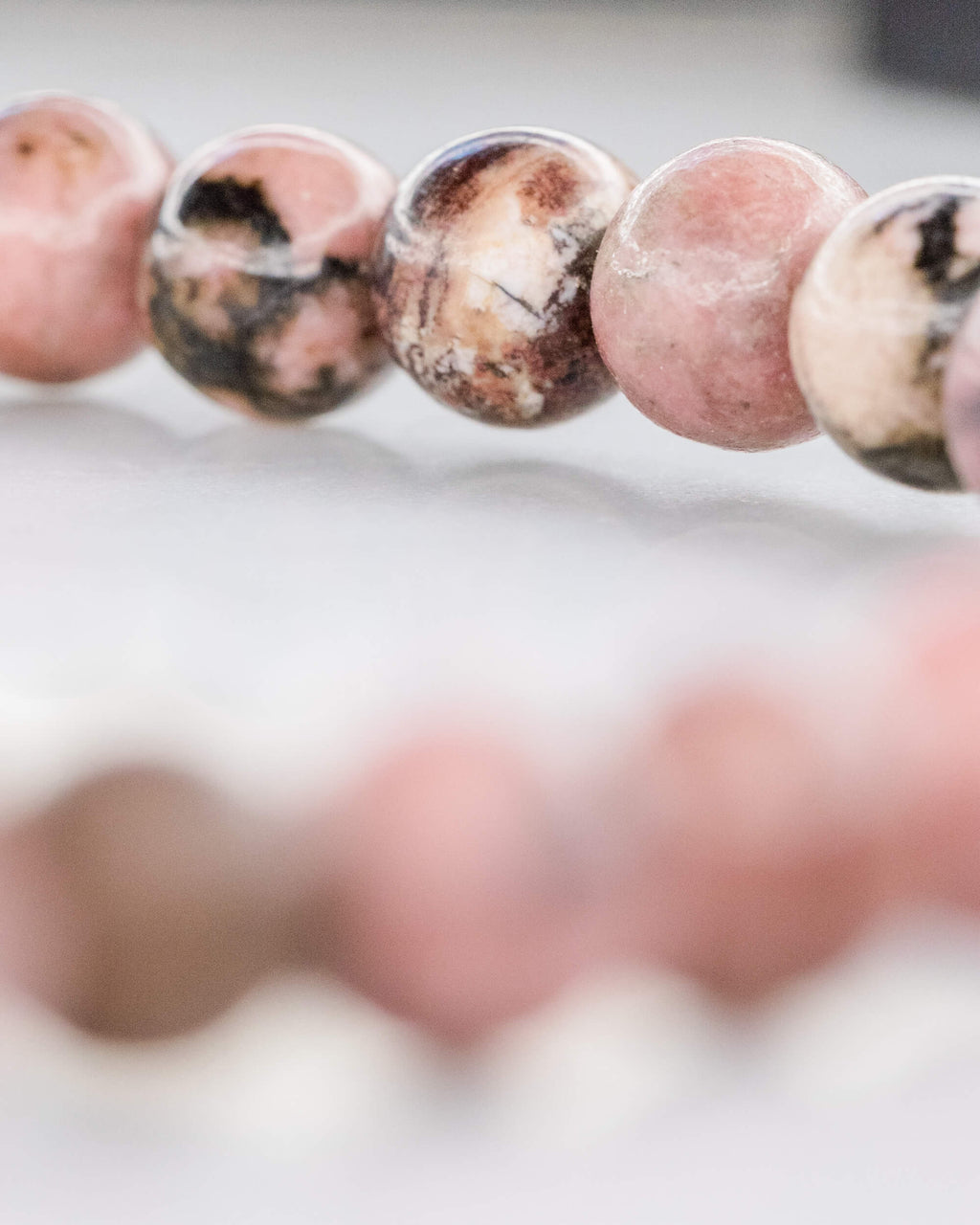Detalle macro de cuentas de Rodonita Encaje Negro en fila, tonos rosa y café