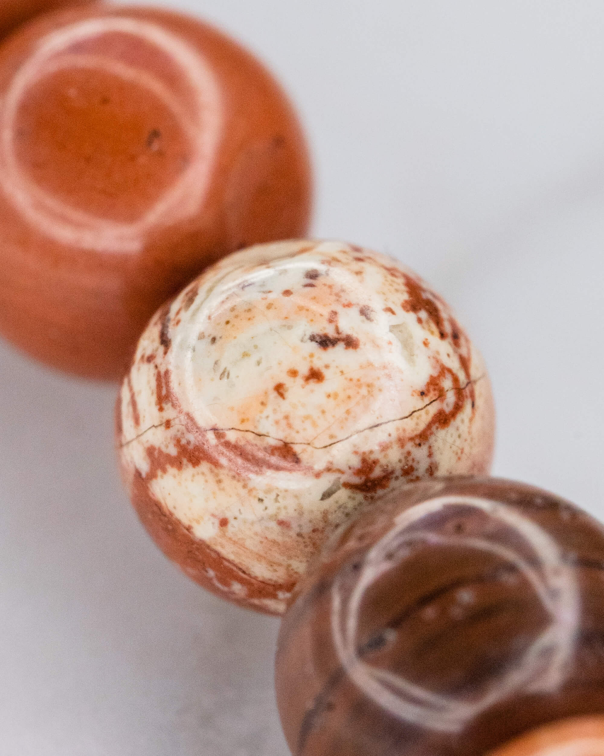 Detalle macro de cuentas de Jaspe Rojo en tonos crema y terracota con grieta natural