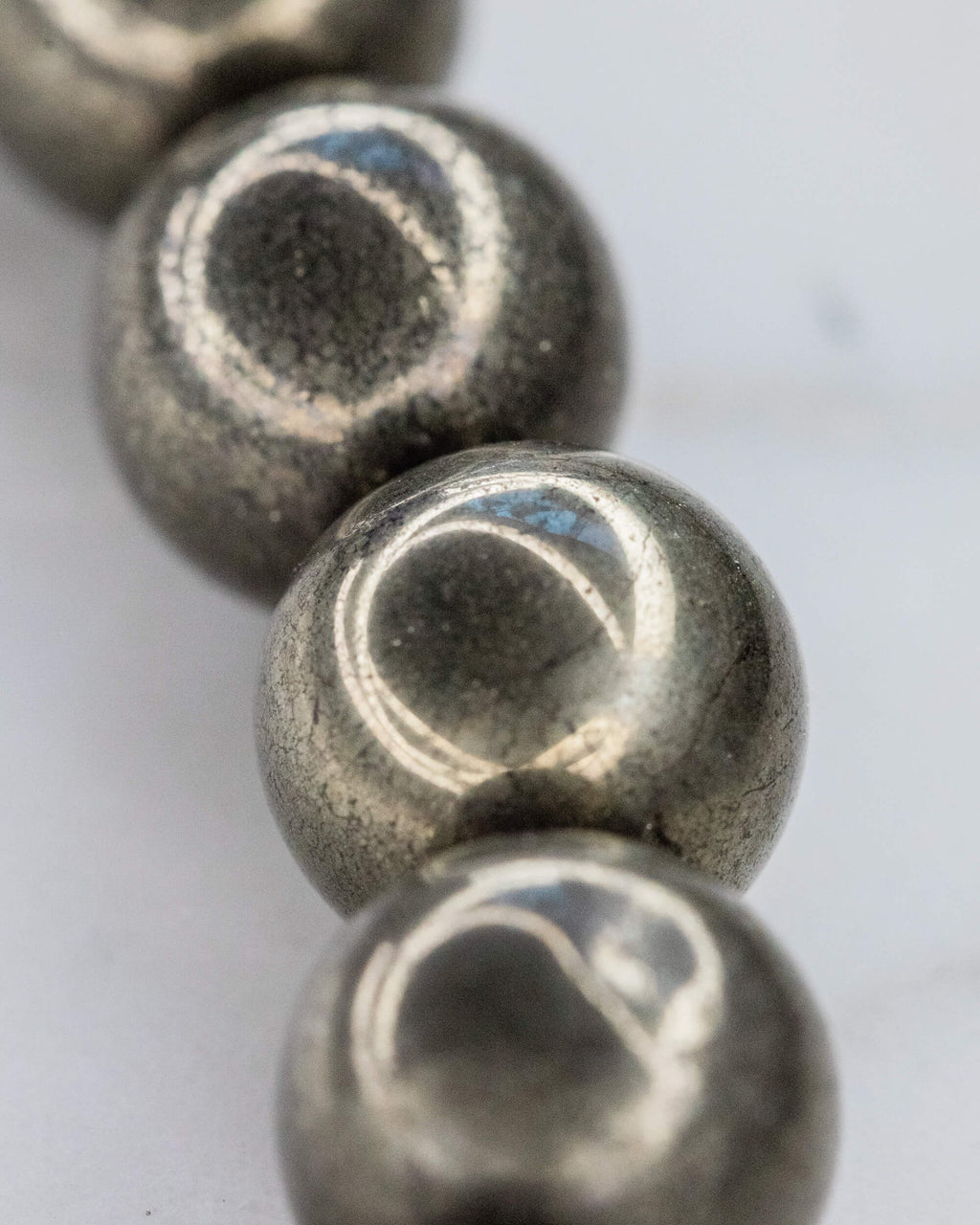 Detalle macro de las cuentas de Pirita en fila, mostrando su superficie metalica