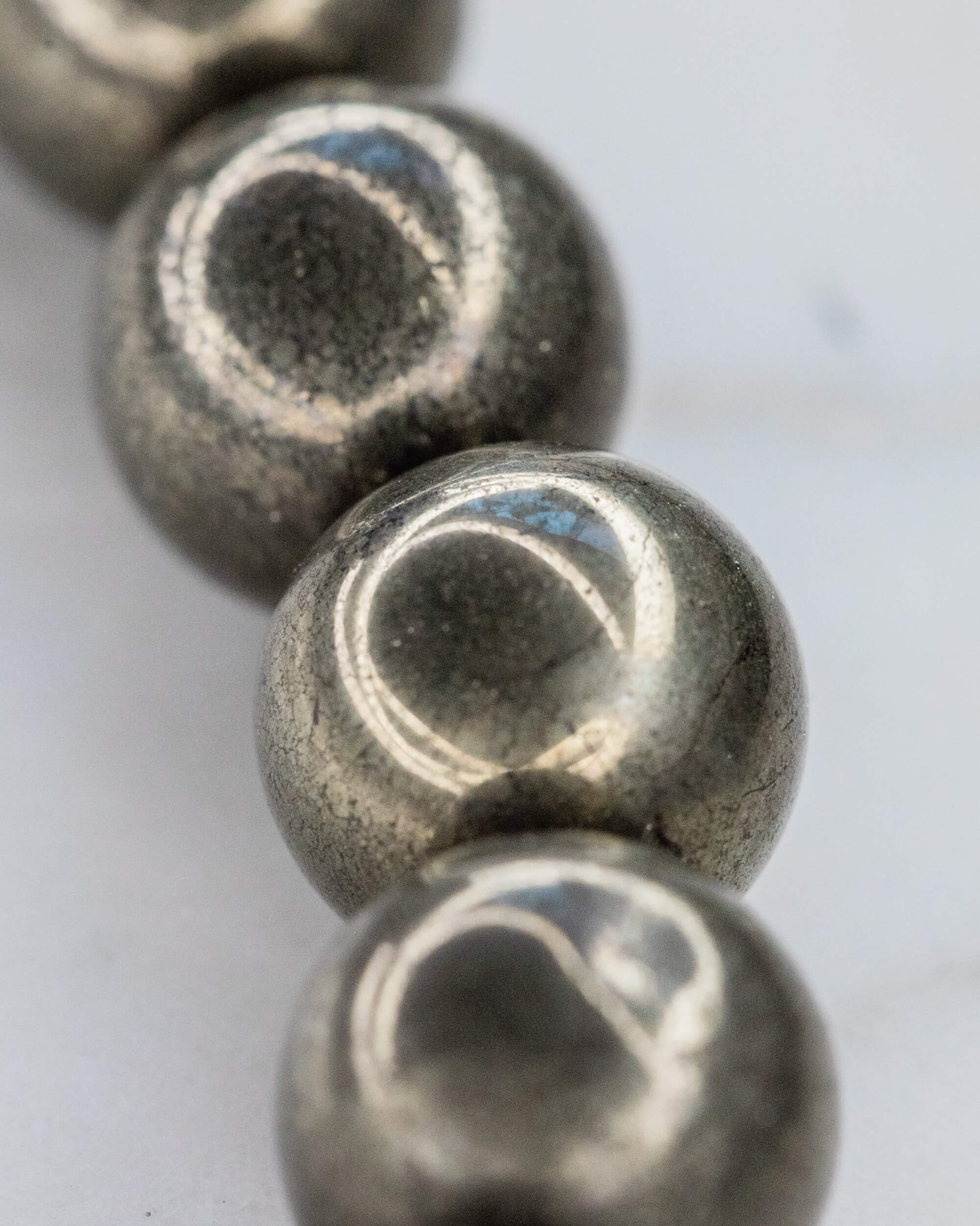Detalle macro de las cuentas de Pirita en fila, mostrando su superficie metalica