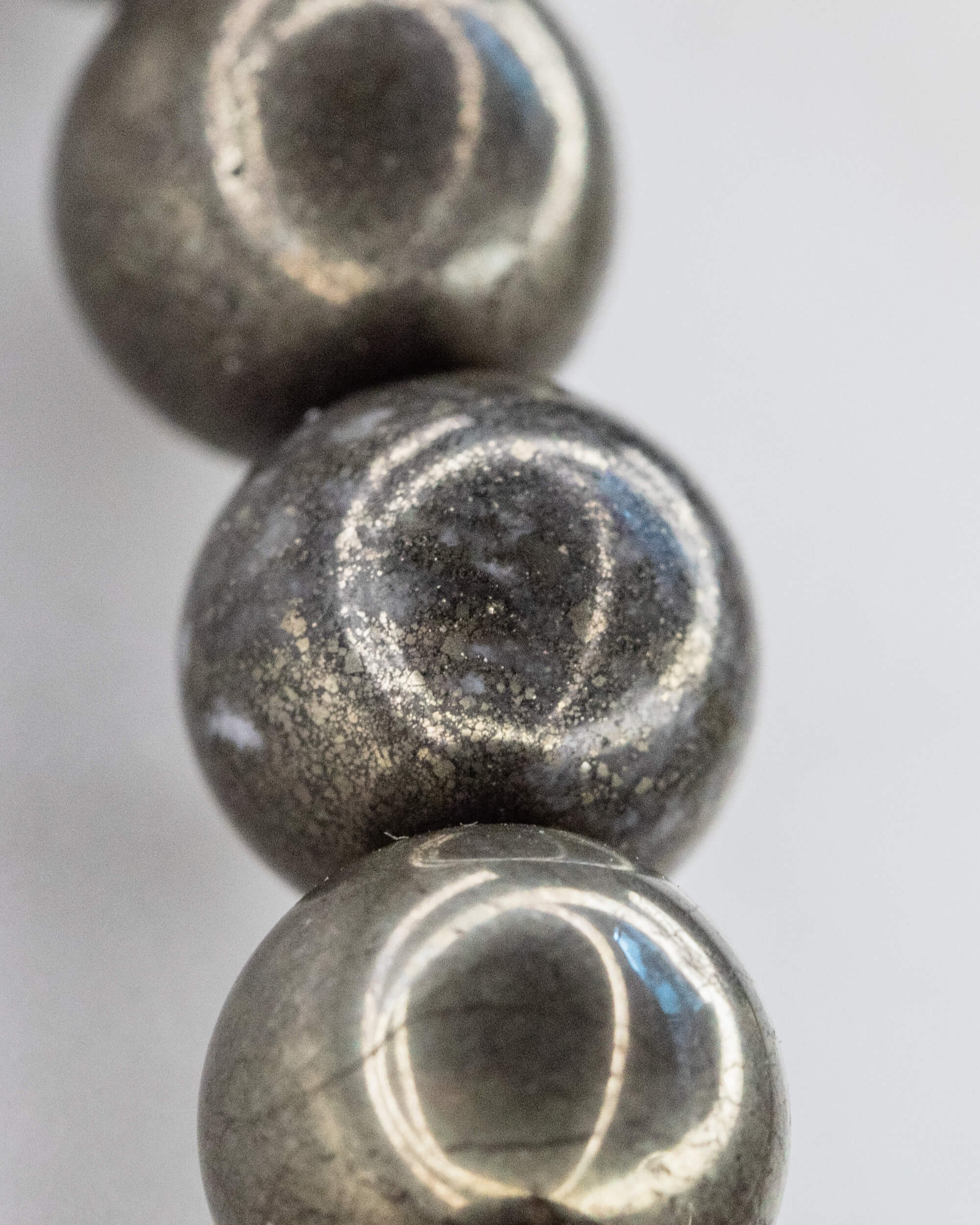 Detalle macro de tres cuentas de Pirita alineadas con reflejos plateados