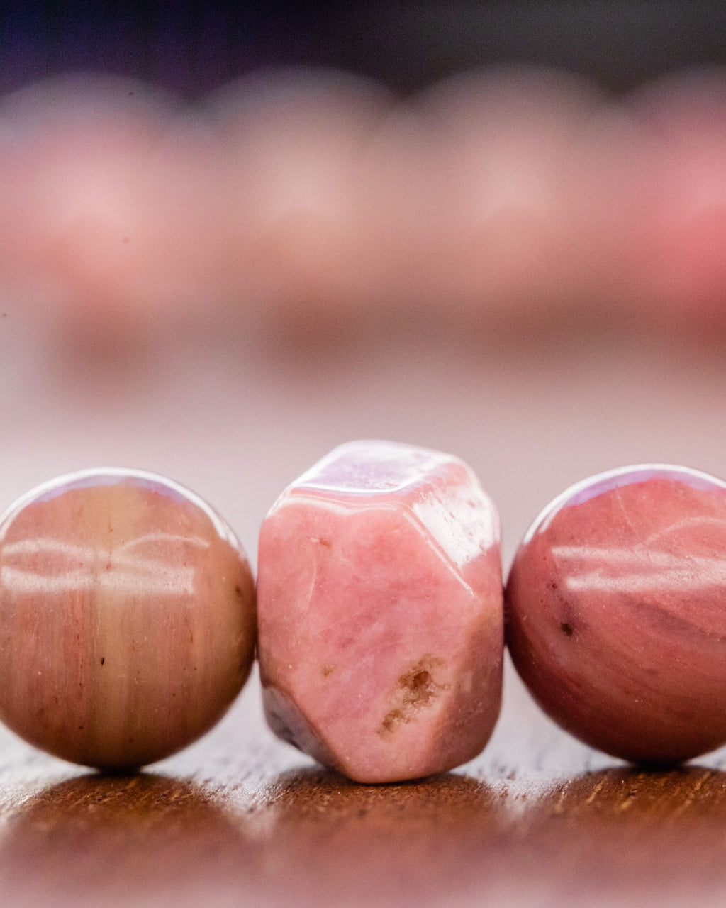 Detalle macro de cuenta facetada de Rodonita Rosa entre cuentas redondas claras
