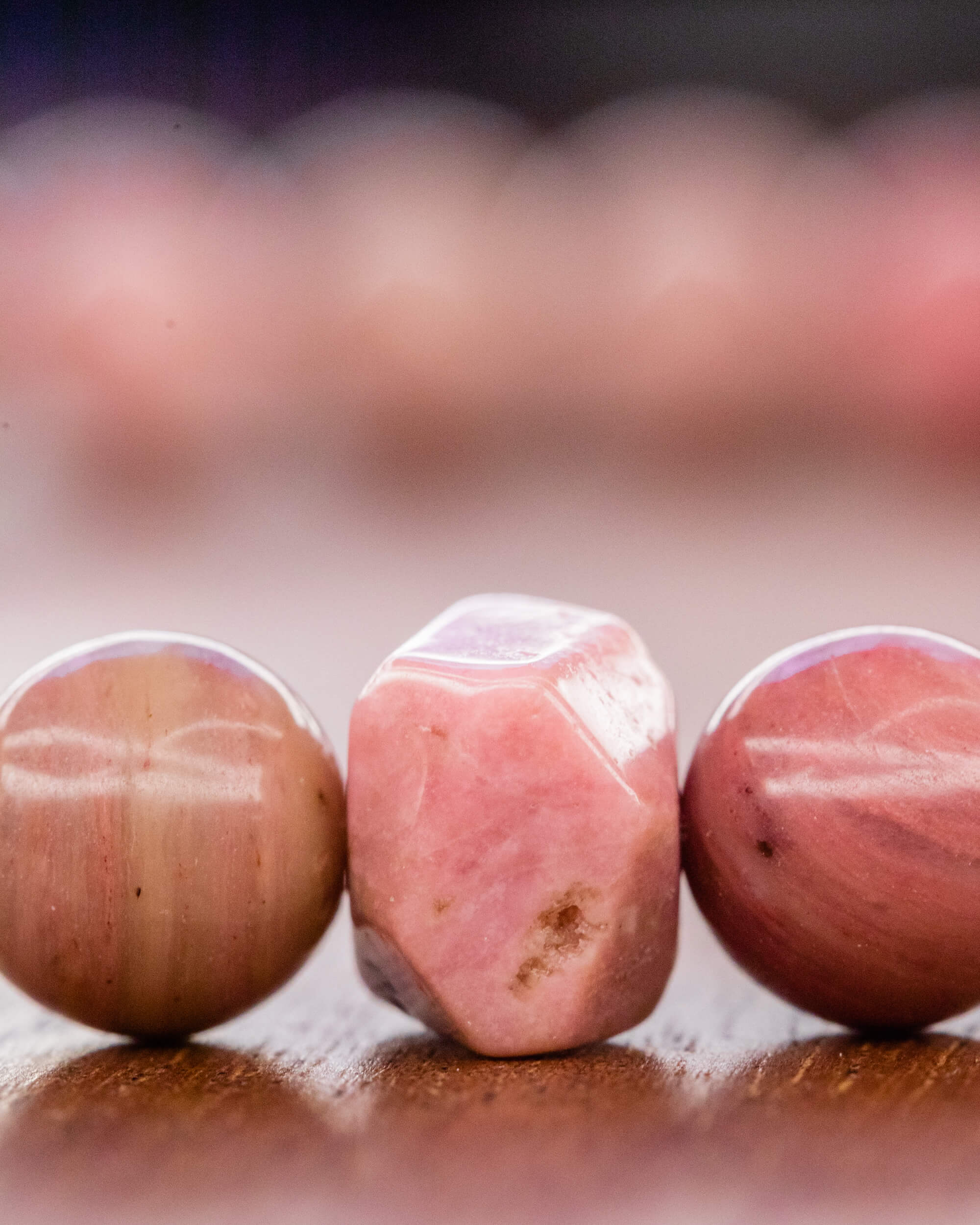 Detalle macro de cuenta facetada de Rodonita Rosa entre cuentas redondas claras