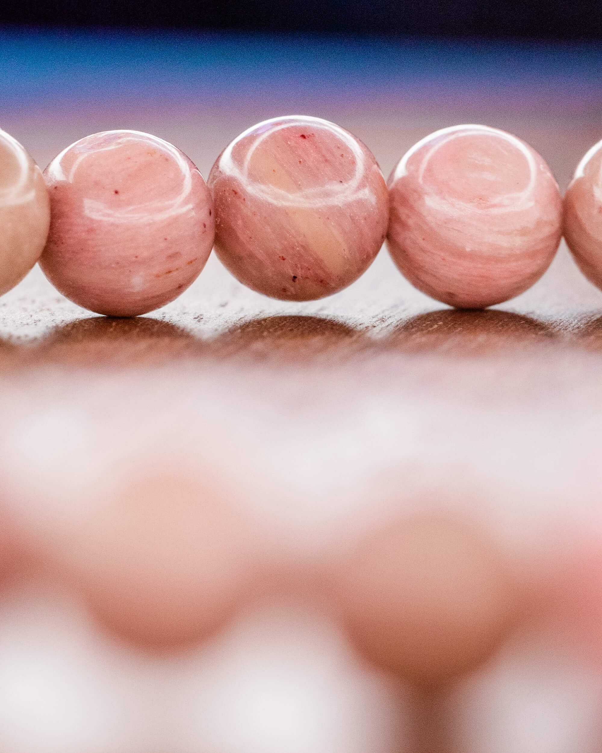Detalle macro de cuentas de Rodonita Rosa sobre superficie de madera