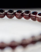 Detalle macro de las cuentas de Granate Rojo con reflejo azulado al fondo