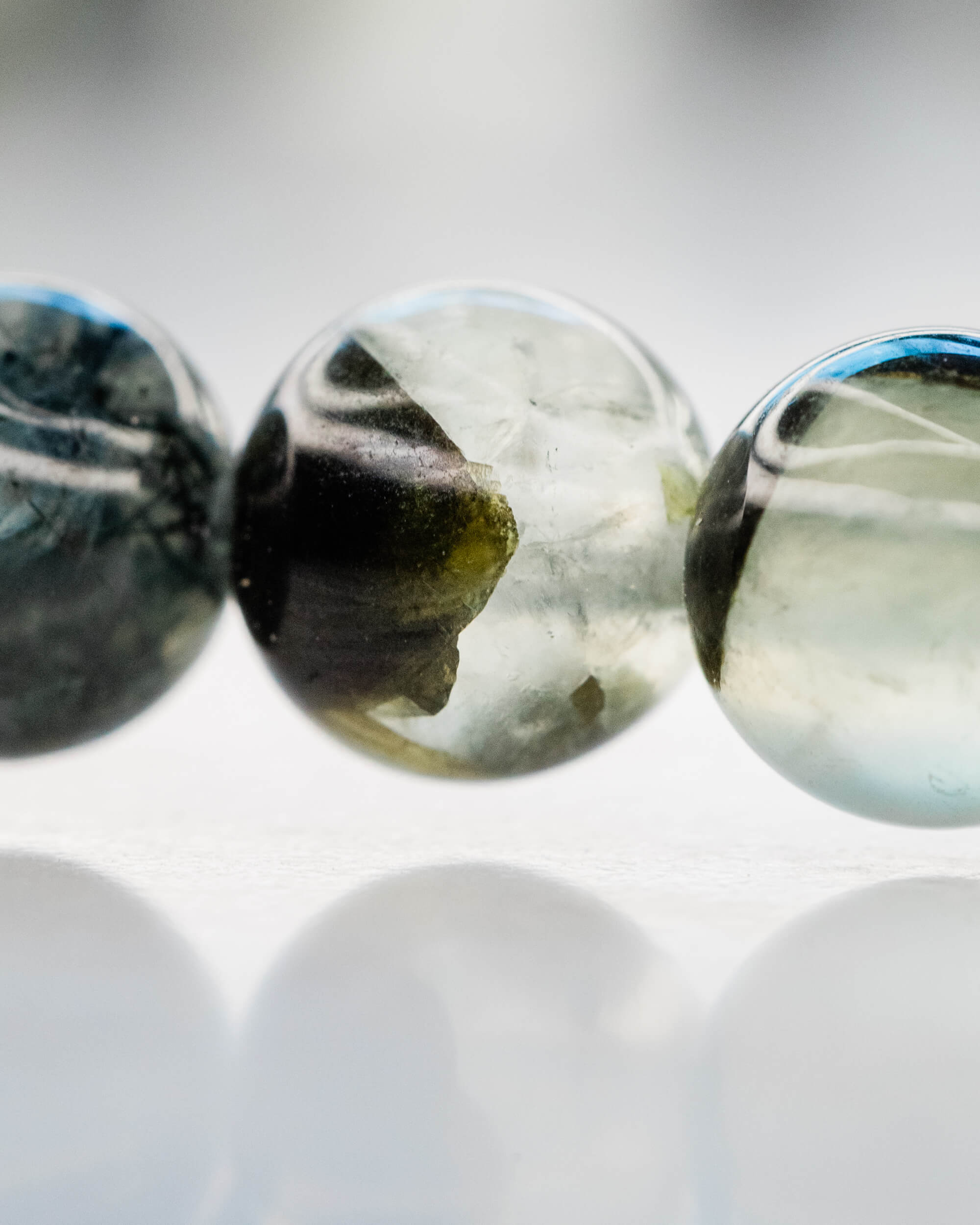 Detalle macro de las cuentas de Prehnita con vetas negras y transparencias