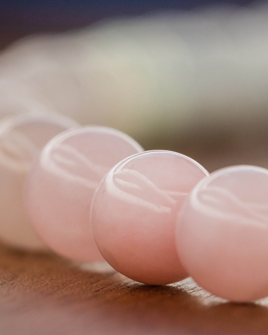 Detalle macro de las cuentas rosas de Morganita sobre superficie de madera