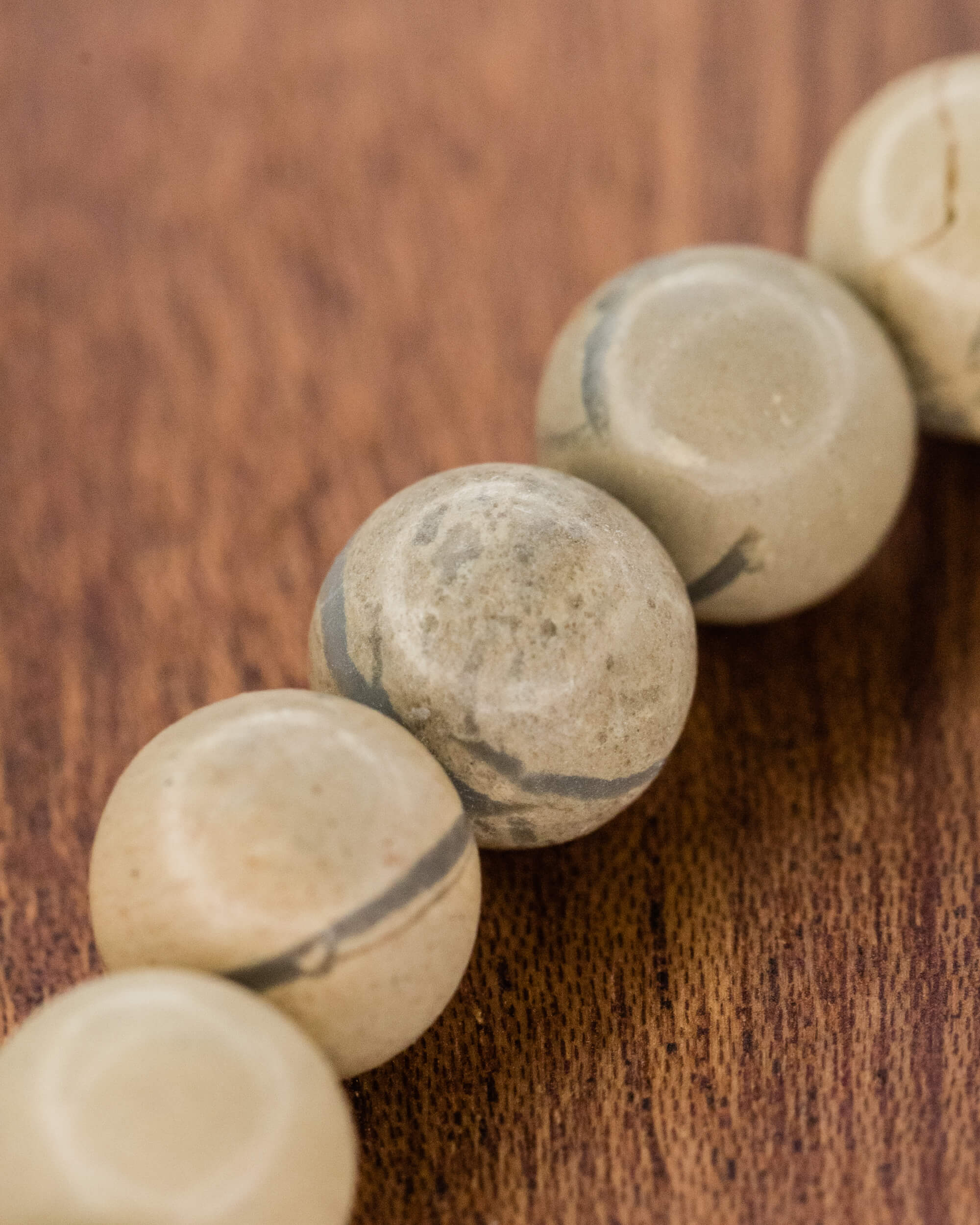 Detalle macro de las cuentas de Shoushan con vetas marcadas sobre madera