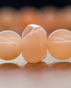 Detalle macro de una cuenta facetada de Piedra Sol Naranja entre cuentas redondas