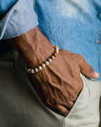 Pulsera de Shoushan puesta en la muñeca, con camisa azul y pantalón verde de fondo