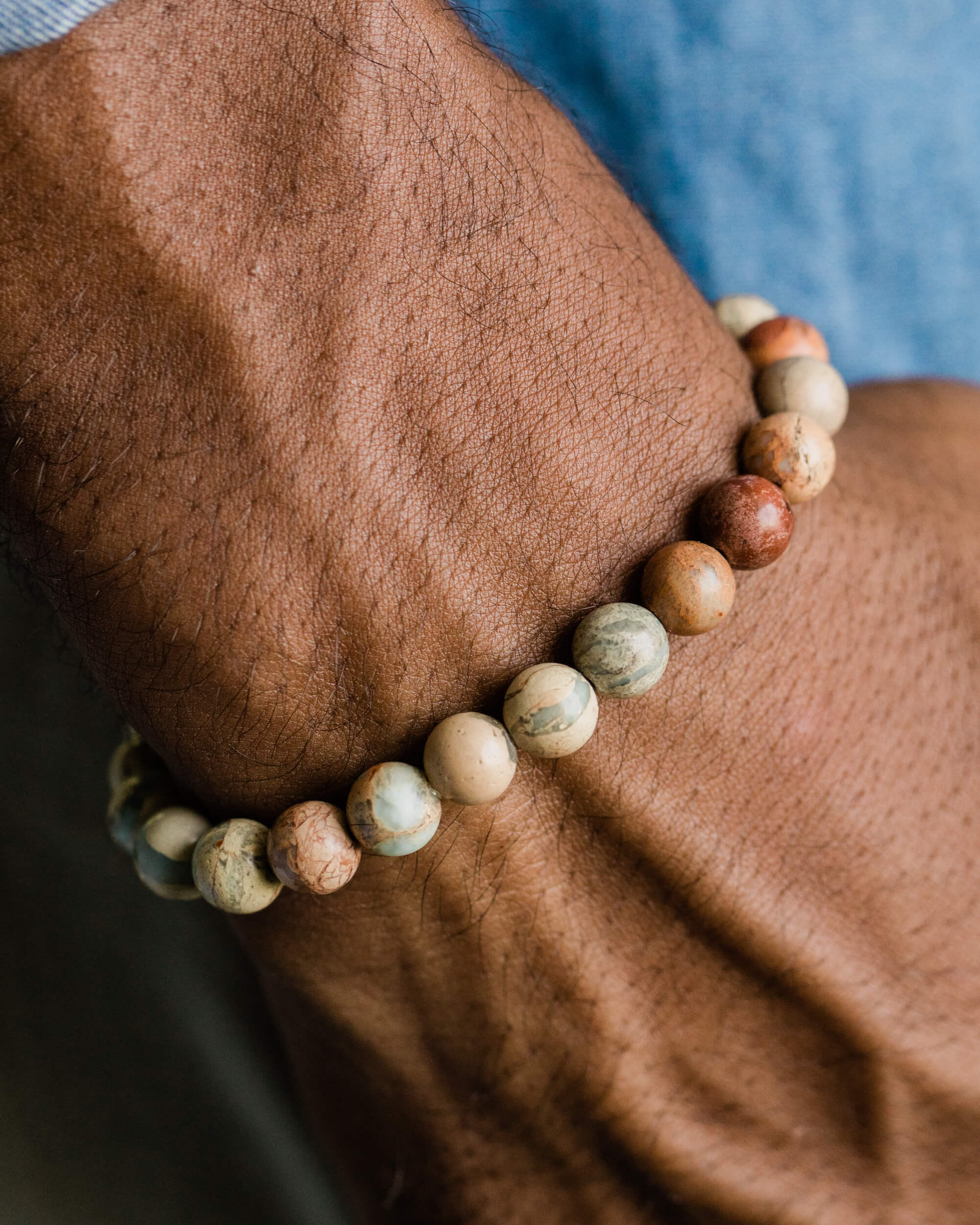 Pulsera de Shoushan puesta en la muñeca, con camisa azul de fondo