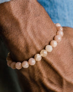 Pulsera de Piedra Sol Naranja facetada puesta en la muñeca, con fondo azul