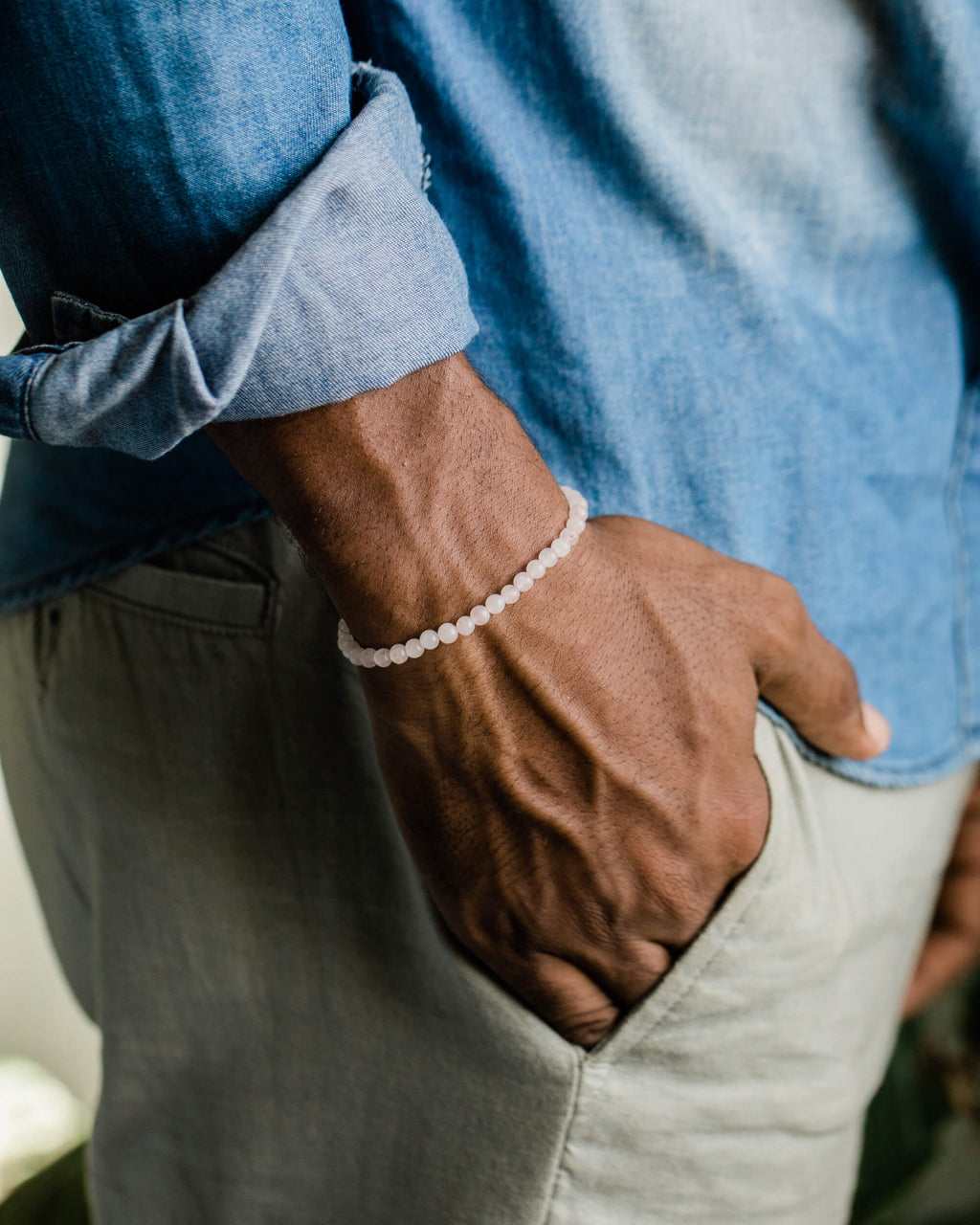 Pulsera de Cuarzo Rosa puesta en la muñeca, mano dentro del bolsillo del pantalon