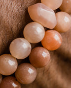 Codificador de Piedra Sol Naranja puesto en la muñeca, cuentas en tonos naranja y crema