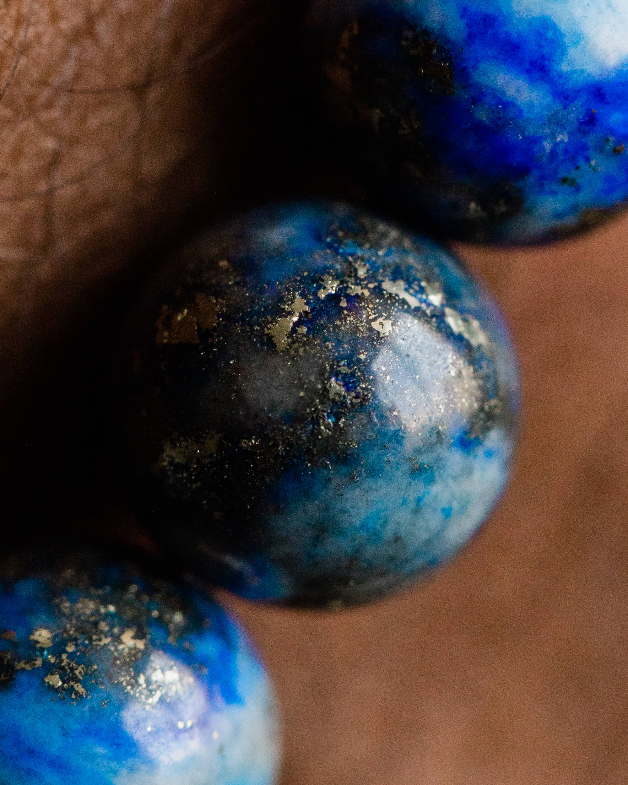 Detalle macro de una cuenta de Lapislázuli con vetas doradas junto a los dedos