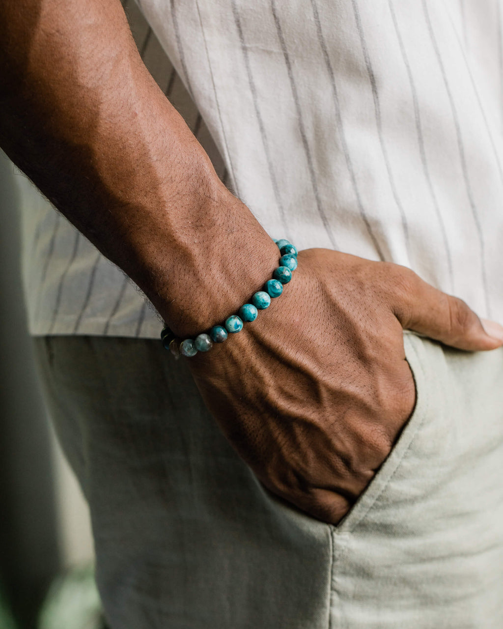 Pulsera de Apatita Azul puesta en la muñeca, con el brazo apoyado en el bolsillo