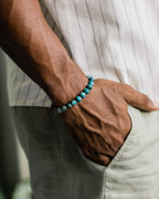 Pulsera de Apatita Azul puesta en la muñeca, con el brazo apoyado en el bolsillo