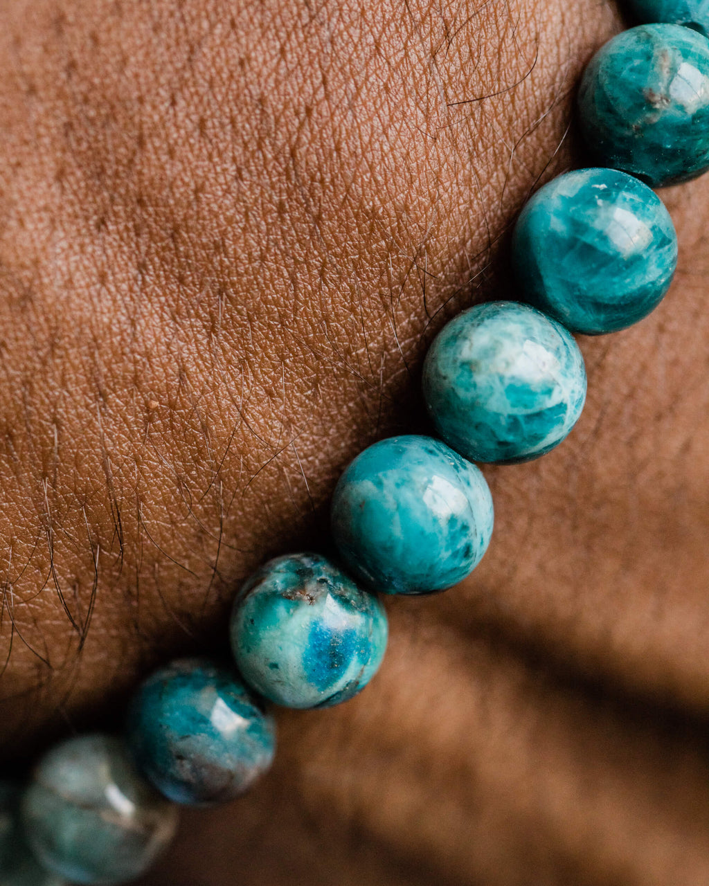 Pulsera de Apatita Azul puesta en la muñeca, detalle cercano de las cuentas