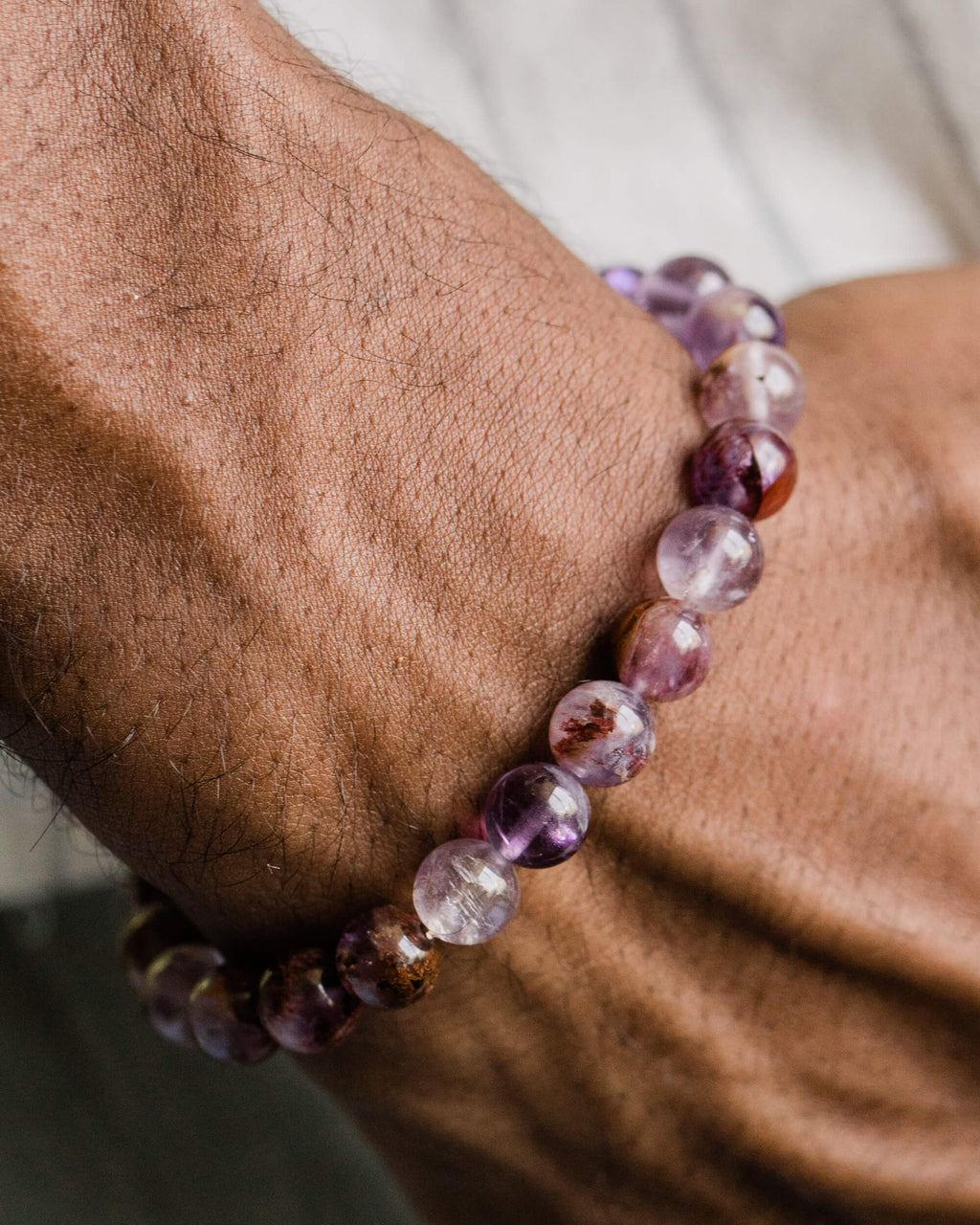 Pulsera de Amatista Fantasma puesta en la muñeca, entre follaje verde
