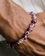 Pulsera de Amatista Fantasma puesta en la muñeca, entre follaje verde