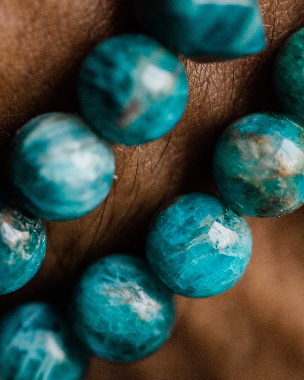 Detalle macro de las cuentas de Apatita Azul puestas sobre la piel de la muñeca