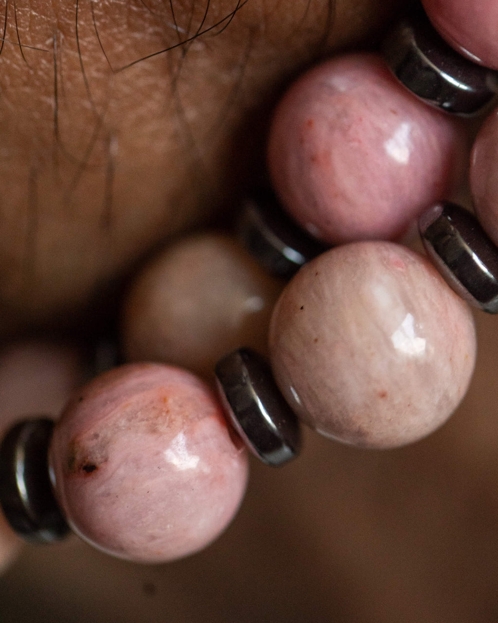 Detalle macro de las cuentas facetadas de Rodonita Rosa y Hematita puesto en la muñeca