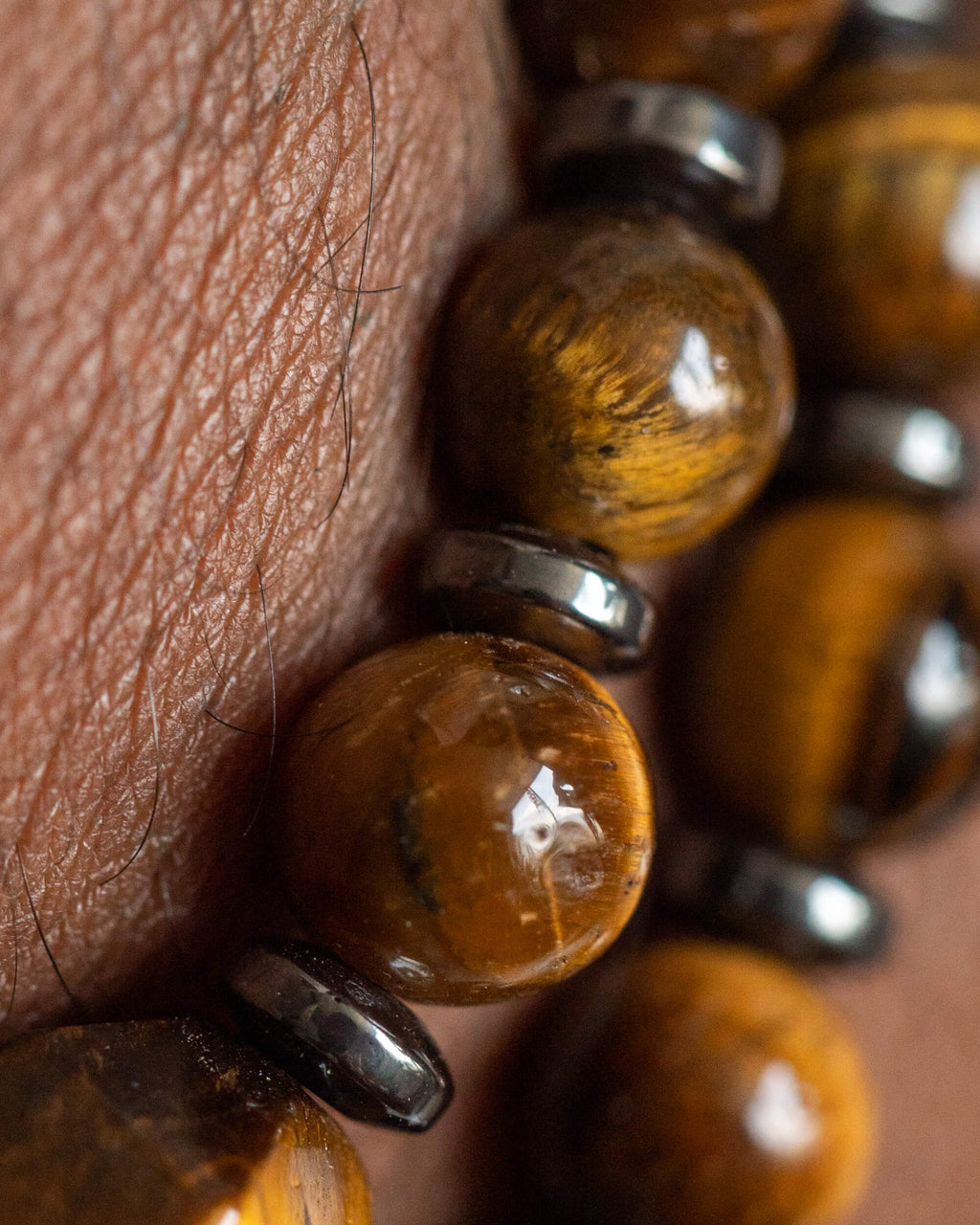 Detalle macro de las cuentas de Ojo de Tigre y separadores de Hematita puesto en la muñeca