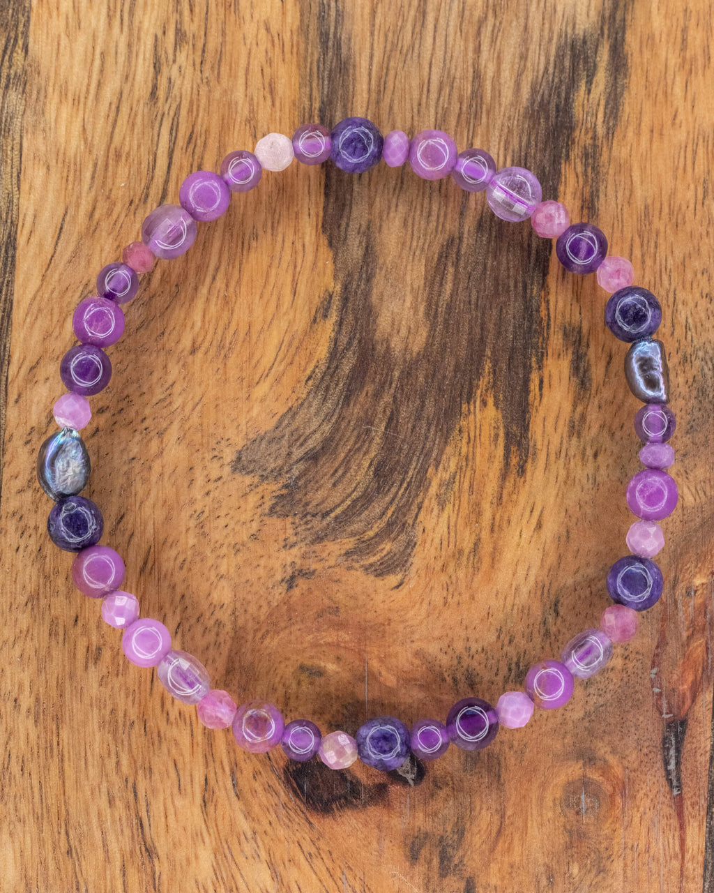 Pulsera mix de minerales morados de 6 mm, pieza completa sobre madera clara