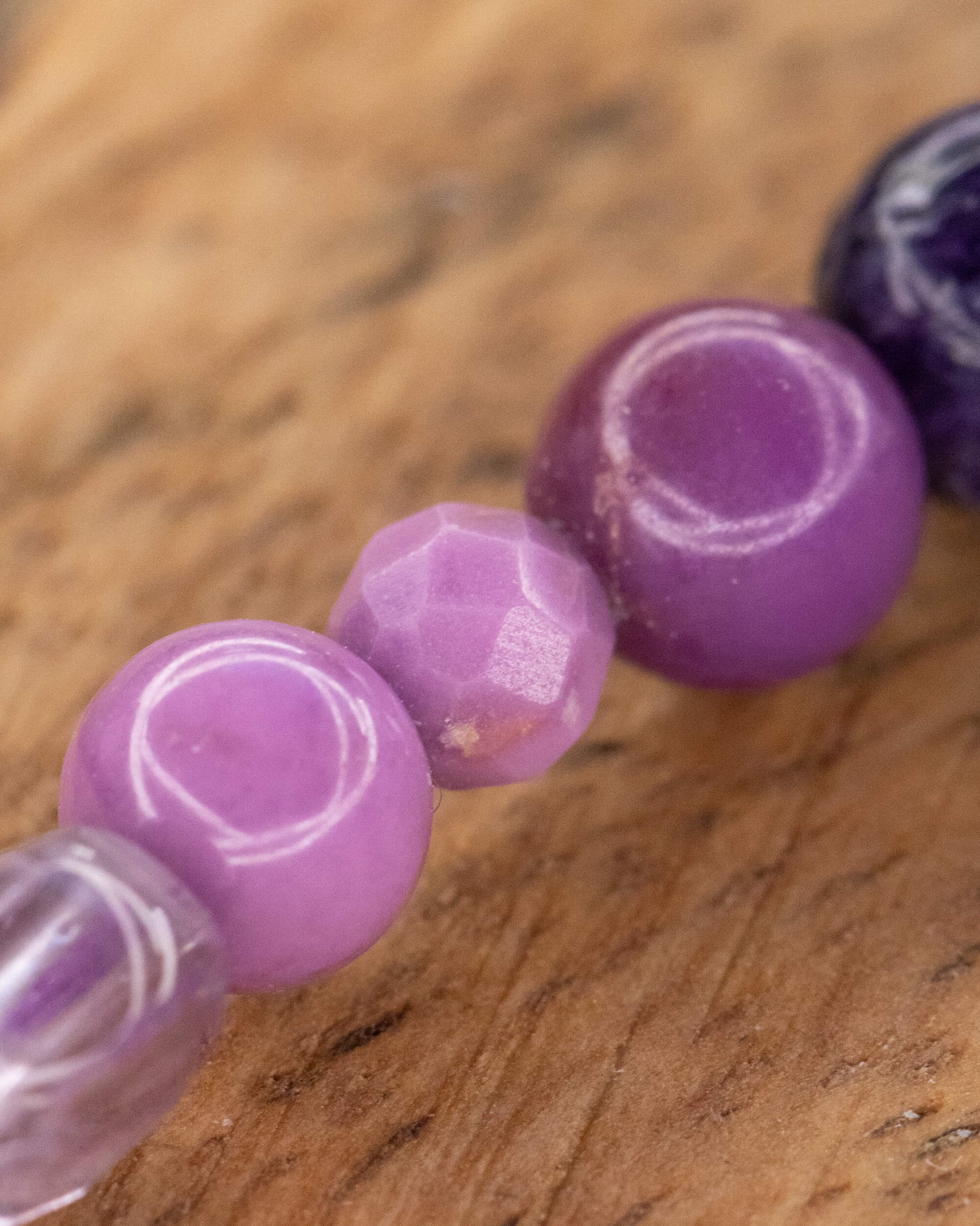 Detalle macro de las cuentas facetadas y lisas en tonos lila y morado
