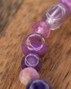 Detalle macro de cuentas moradas facetadas y translúcidas de la pulsera mix