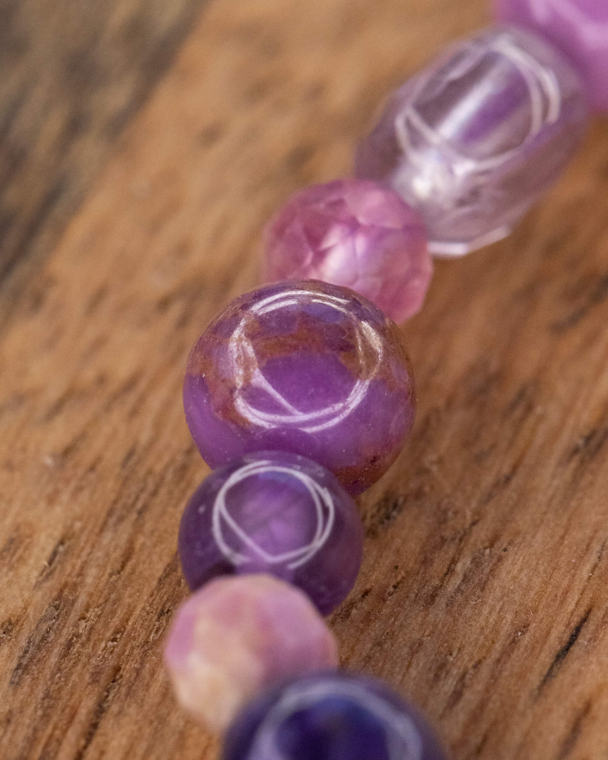 Detalle macro de cuentas moradas facetadas y translúcidas de la pulsera mix