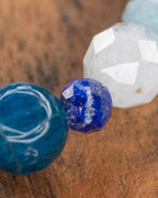 Detalle macro del Mix de Minerales Azules, cuenta de Apatita Azul junto a Lapislázuli facetada