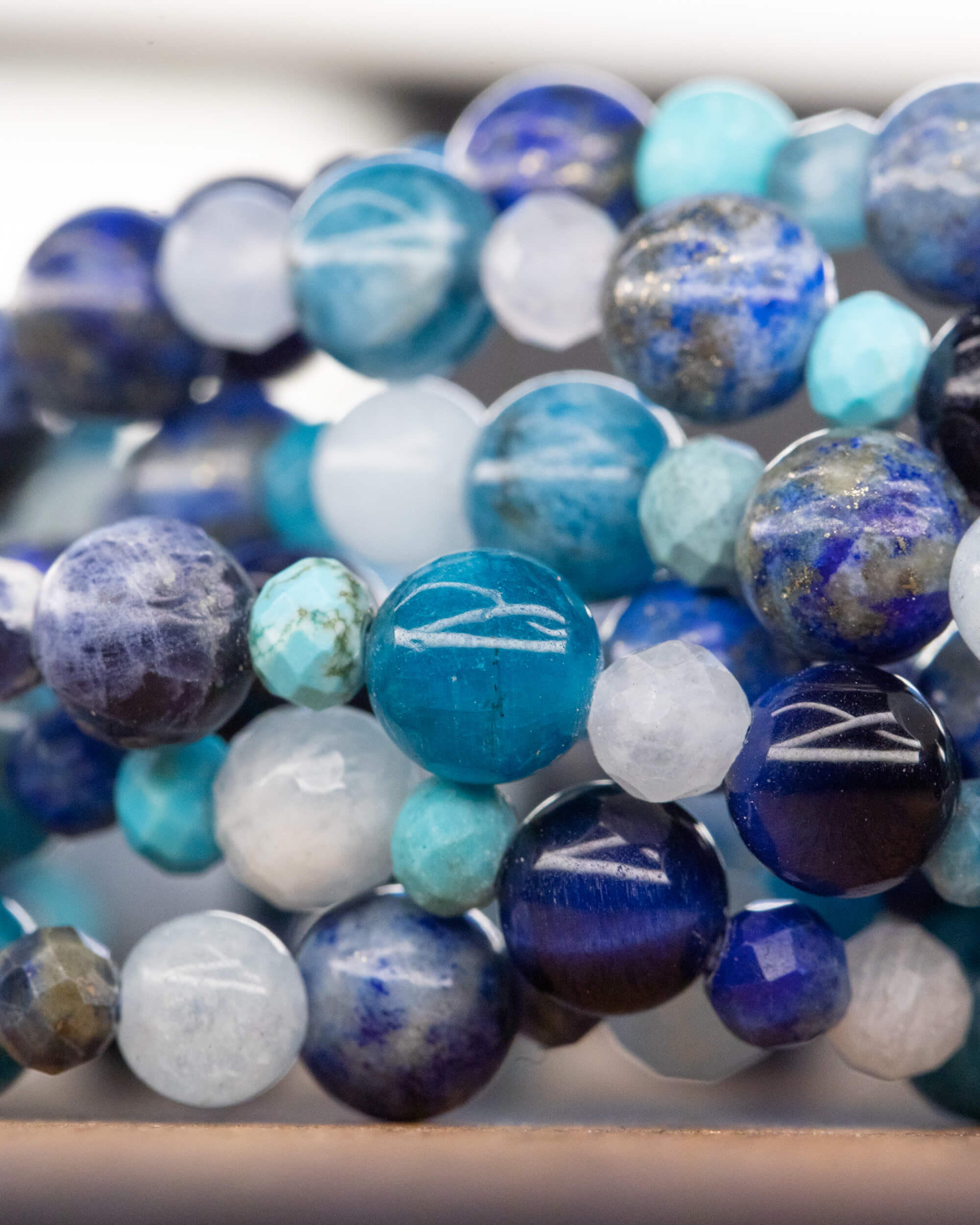 Detalle macro de las cuentas del Mix de Minerales Azules, curva de la pulsera desenfocada al fondo