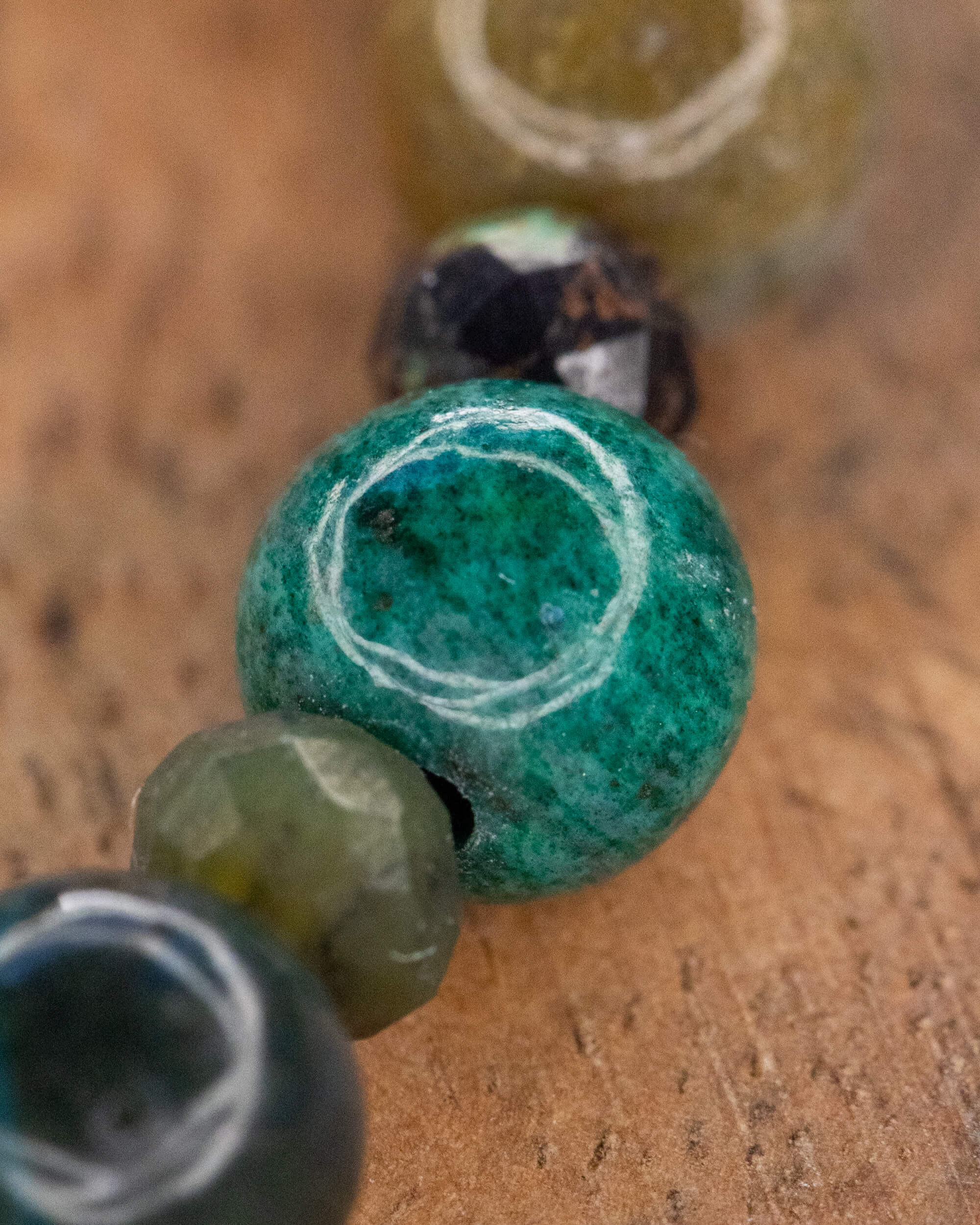 Detalle macro de una cuenta verde de Jaspe Kambaba entre cuentas de Ágata Musgosa