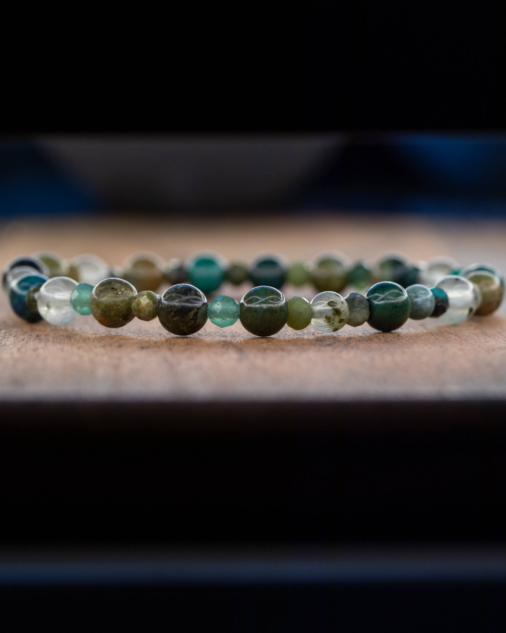 Pulsera Mix de Minerales Verdes puesta de perfil sobre superficie de madera